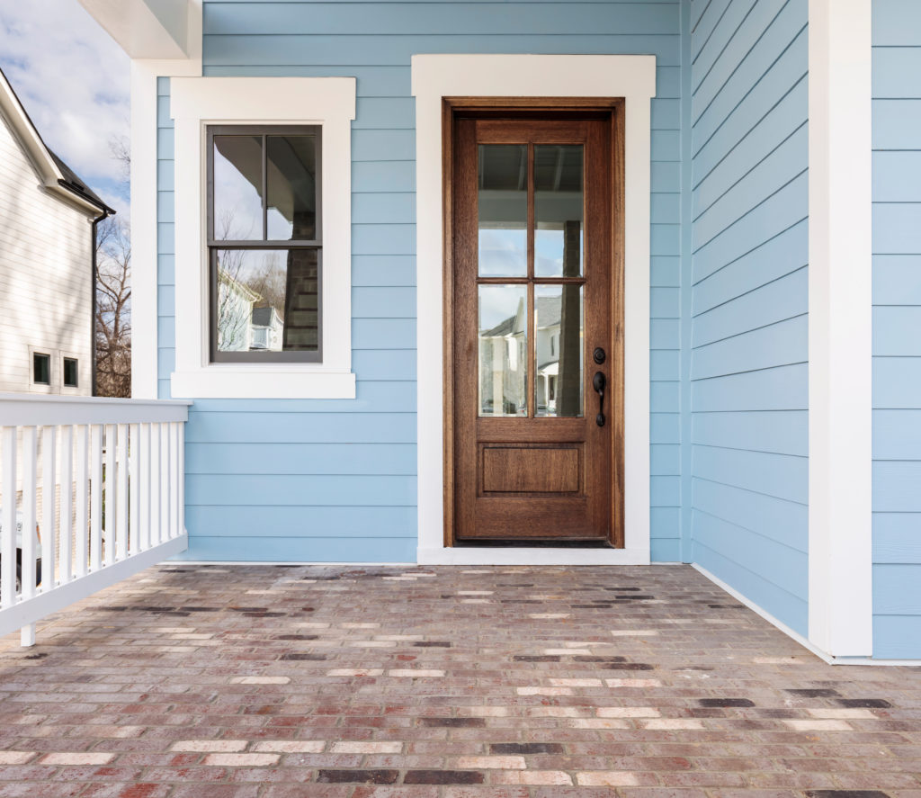 Pale blue house exterior with white trim and brown door