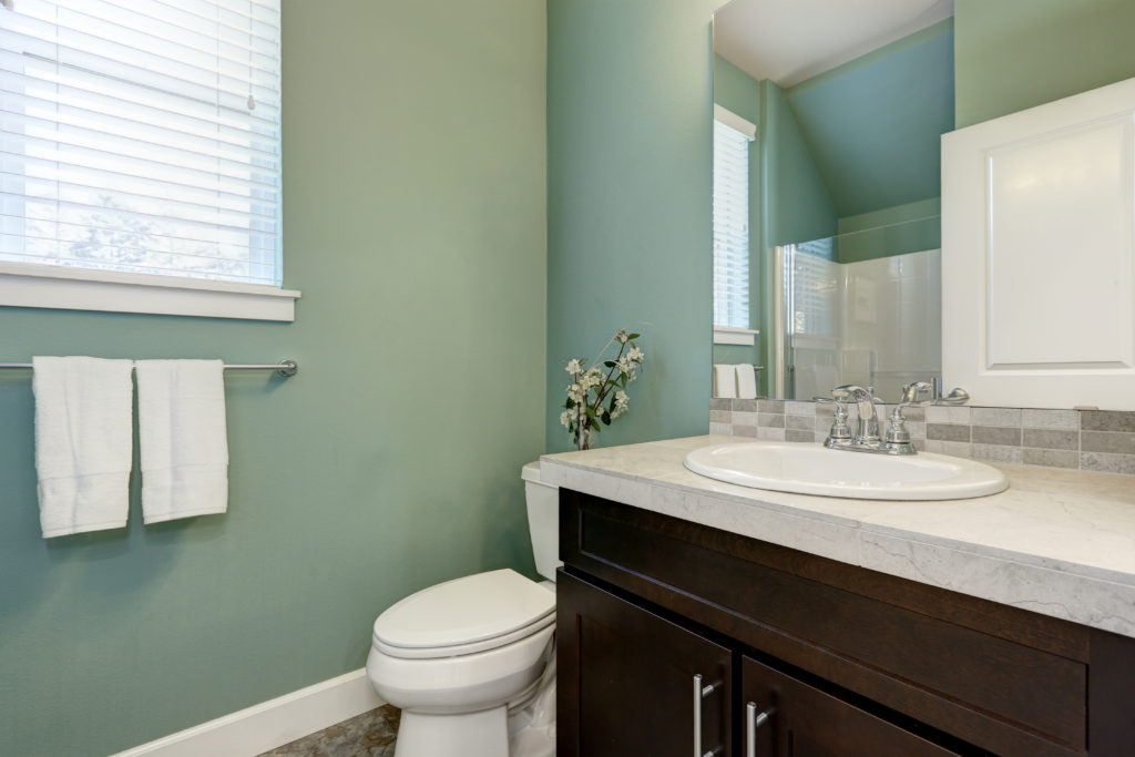 Mint green bathroom with brown cabinets