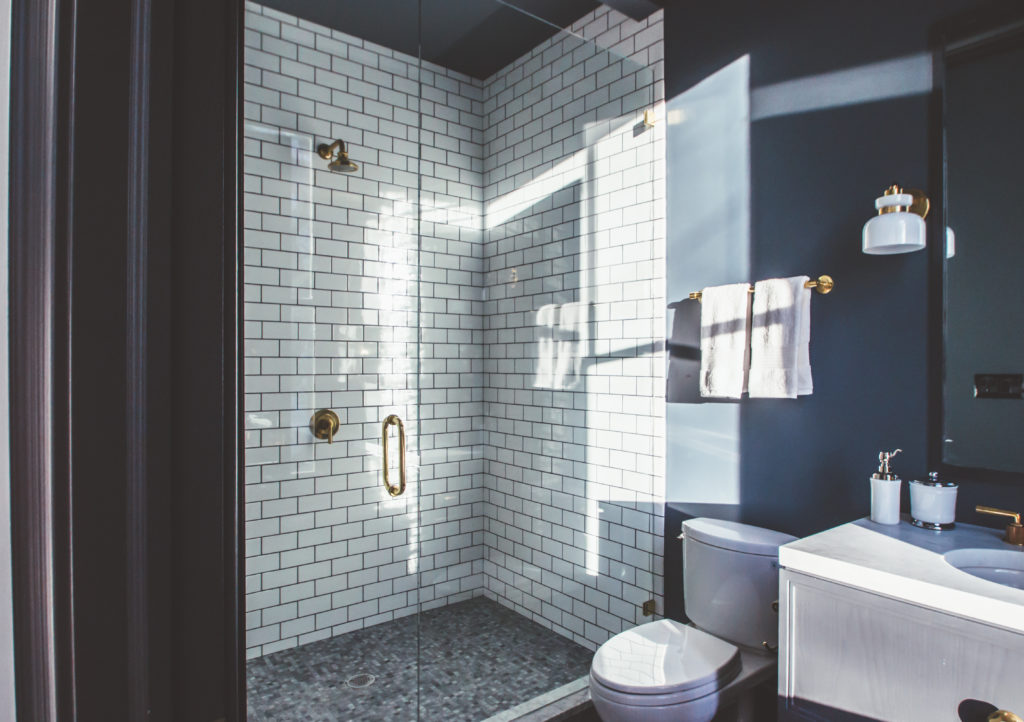 Home bathroom with dark blue walls and white subway tile shower