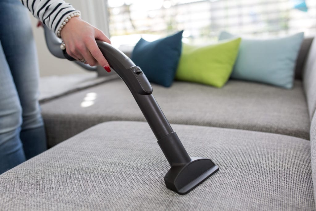 Woman vacuuming gray couch