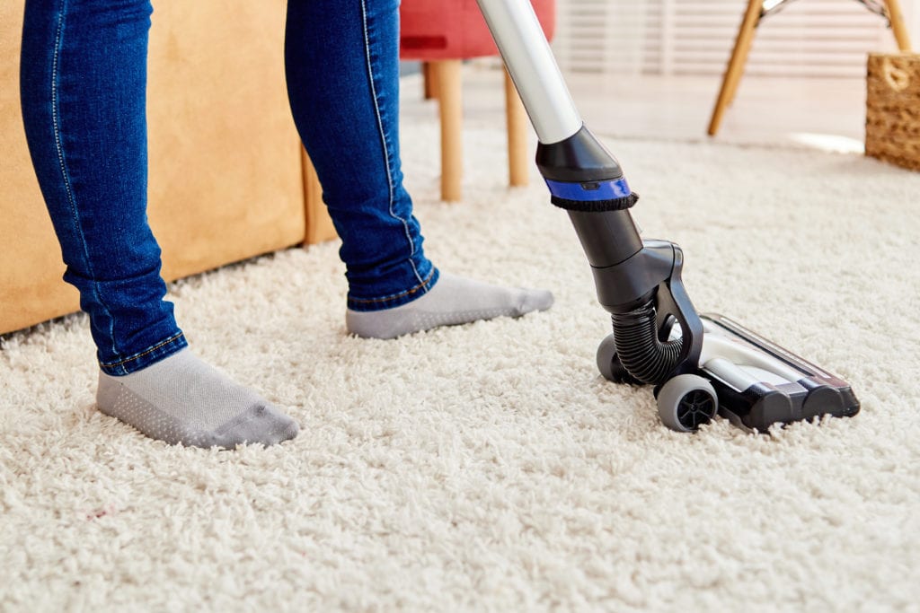 Woman vacuuming carpet in living room