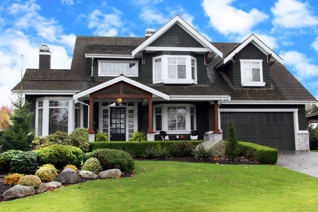 Upscale exterior of dark brown house with bright green lawn