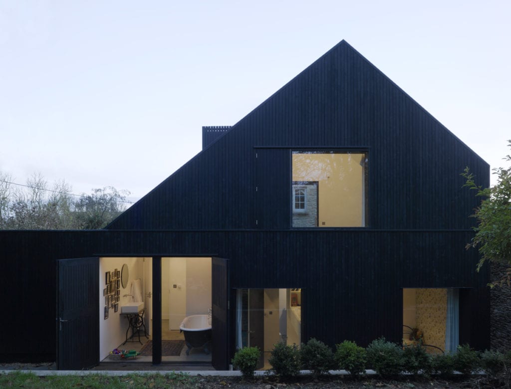 Exterior of black house, with windows showing interior rooms