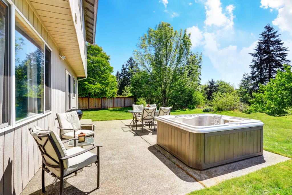 Backyard patio and lawn area with hot tub