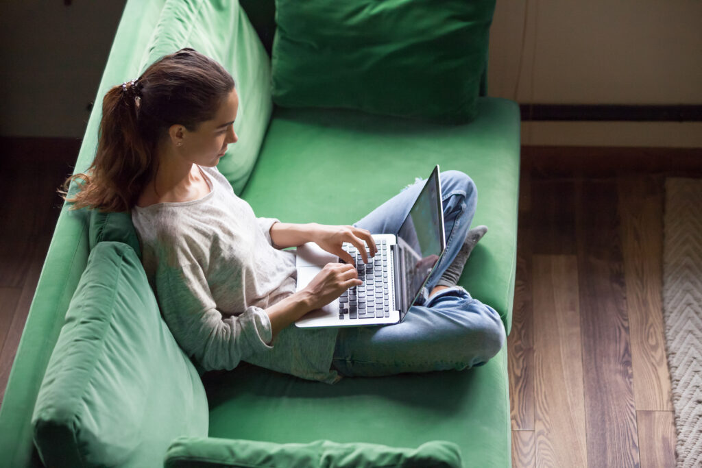 girl sitting on green couch with laptop