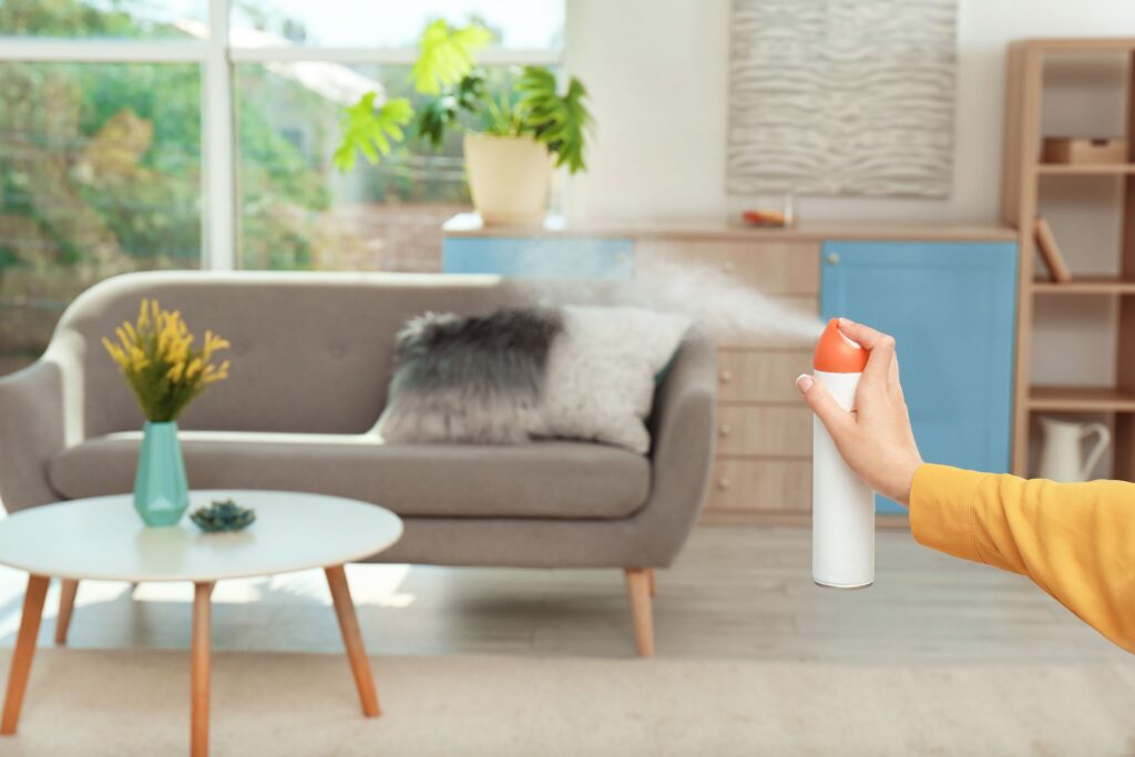 Person wearing glove sprays air freshener in living room