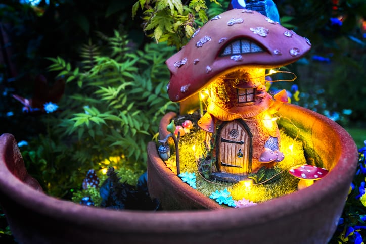 Lighted fairy house in broken garden pot at night