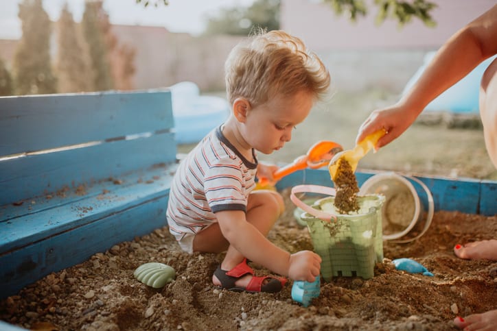 Child plays in his backyard sandbox