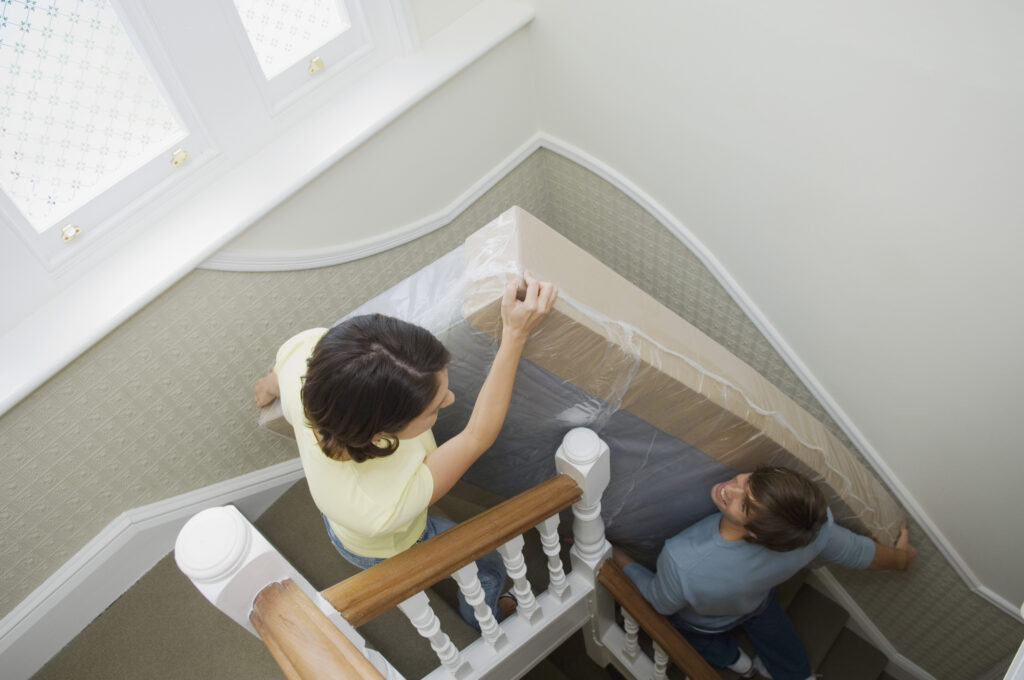 A couple moves their mattress into their new home