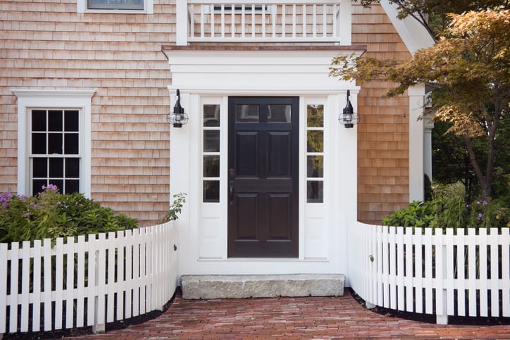 Entryway of brick New England home with picket fence