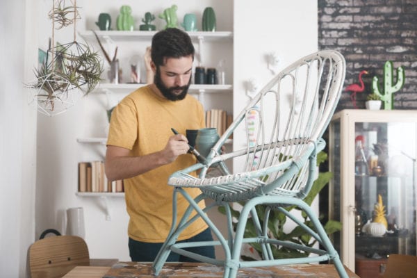 Bearded man painting a chair with milk paint