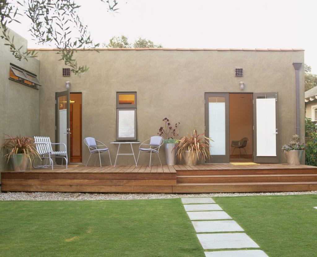 Concrete path leads to modern home in backyard