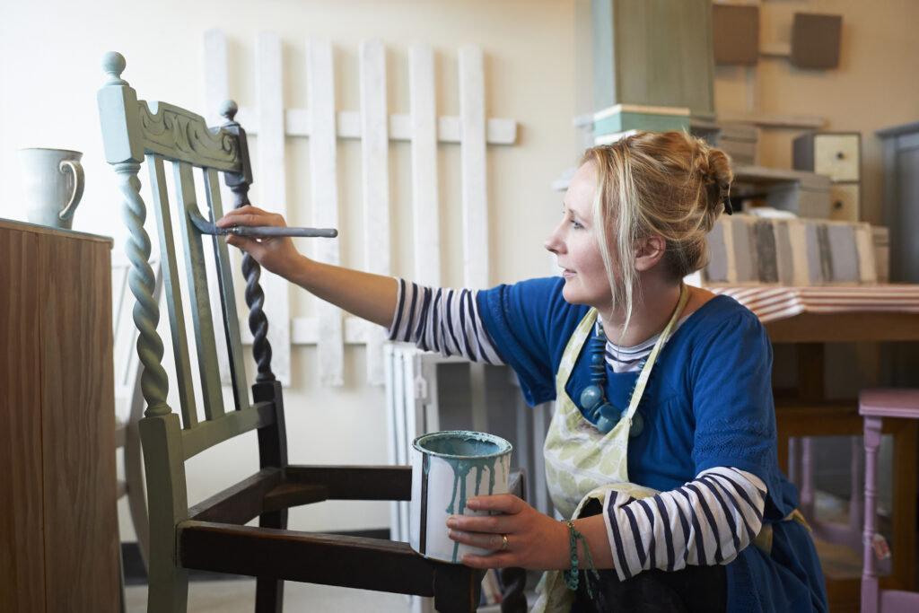 Woman painting chair in workshop