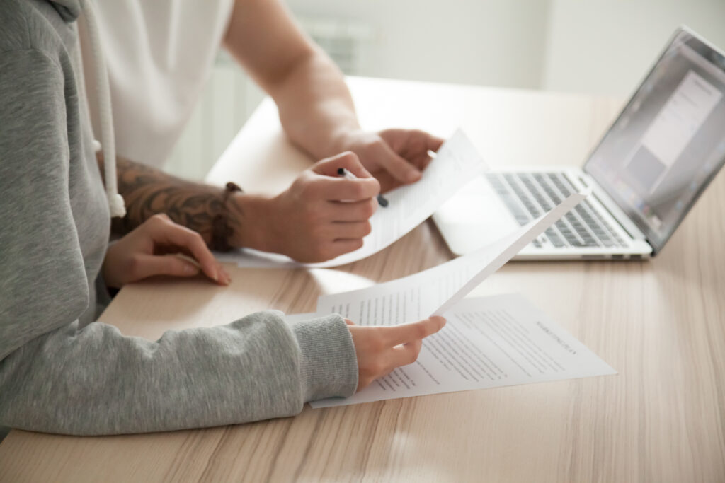 Couple reading over legal documents with pen and laptop