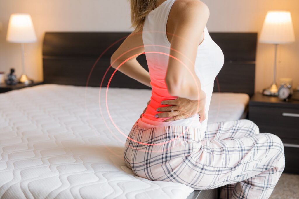 Woman with back pain sitting on mattress