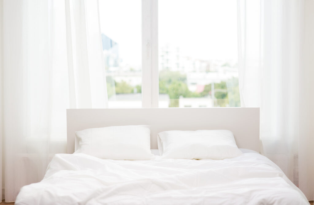 White bed against a window overlooking the city