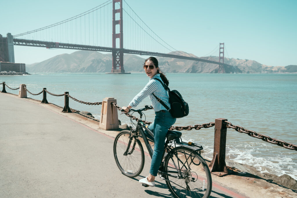 Woman biking in San Francisco in front of Golden Gate Bridge