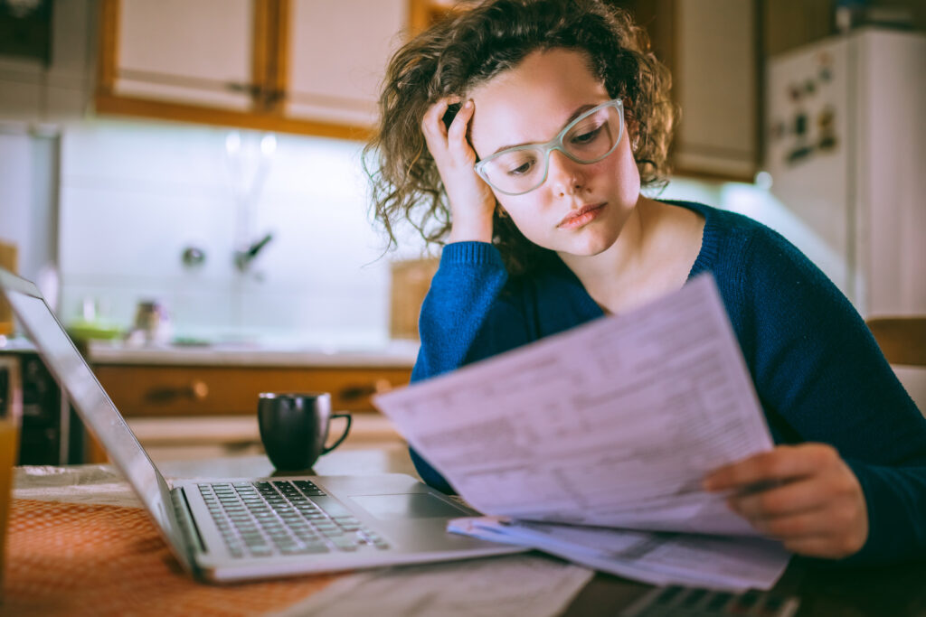 Young brunette curly female reading her rent lease, looking stressed