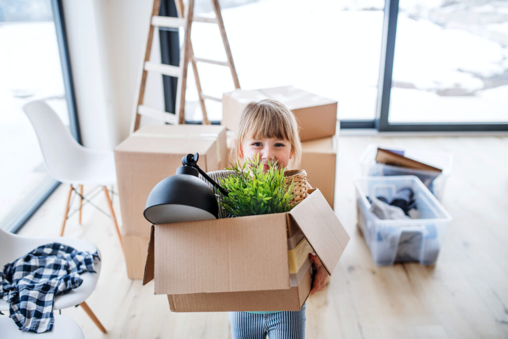 Small cute girl carrying a full box when moving in a new home.