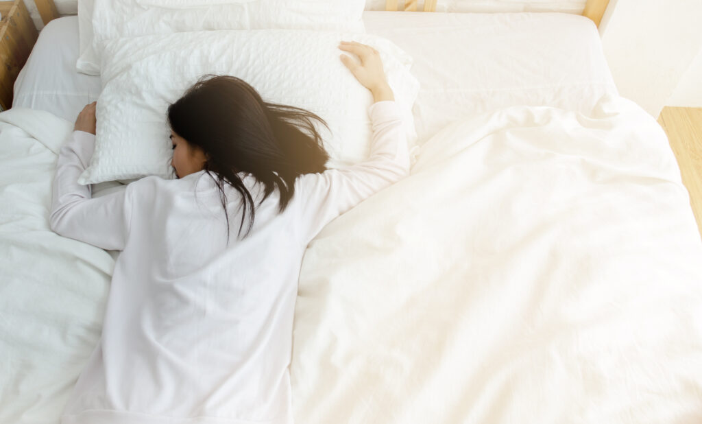 Lady lying face down on the bed, with morning light shining through