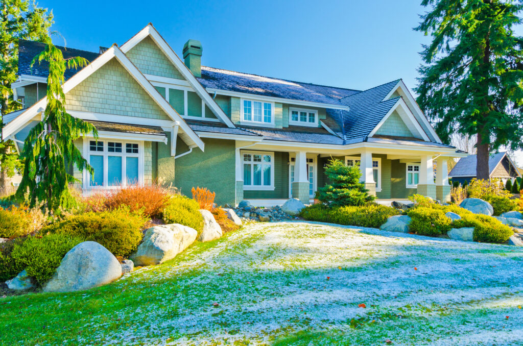 Lawn in front of nice house covered in thin layer of snow or ice