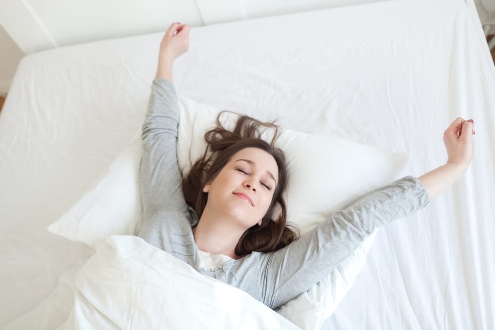 Woman wakes up and stretches on her Leesa mattress