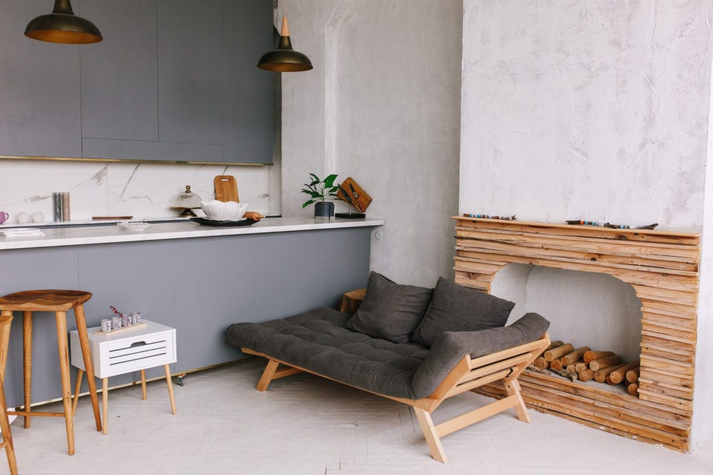 Interior of the modern loft kitchen-studio in the apartment. Room, furniture, sofa near wooden fireplace.