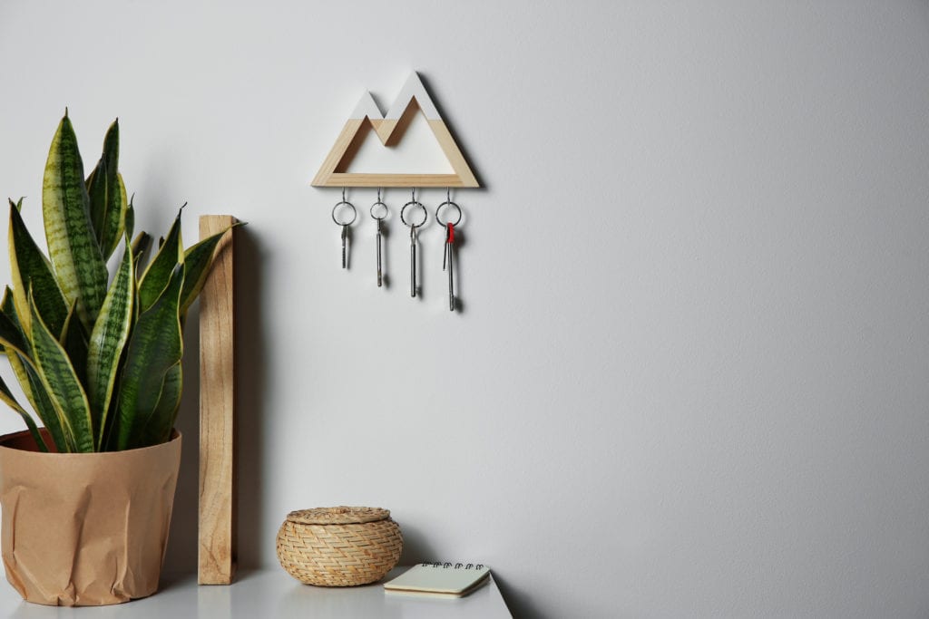 Wooden key holder on light wall indoors. Space for text