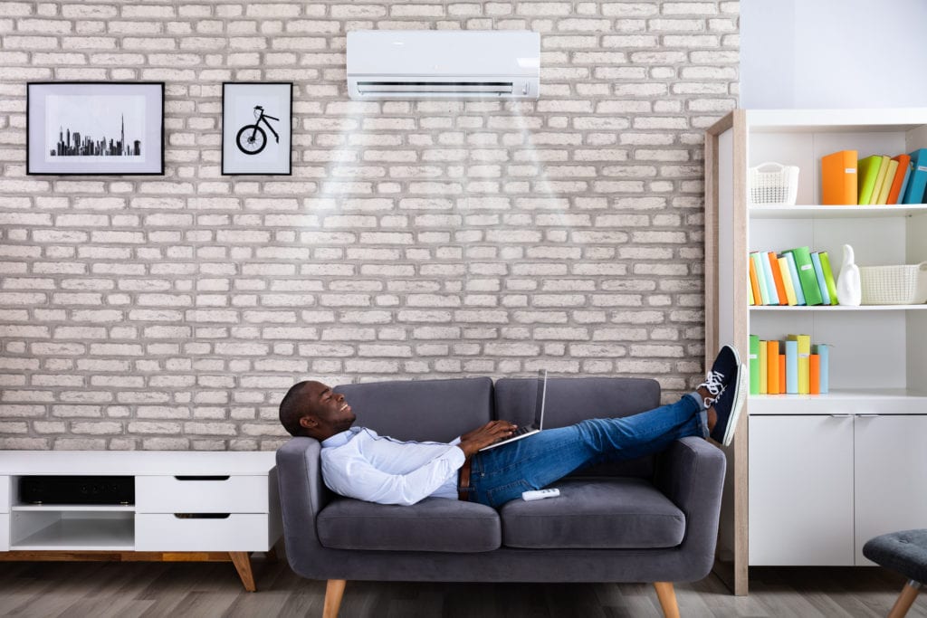 Man on couch enjoying ductless cooling unit