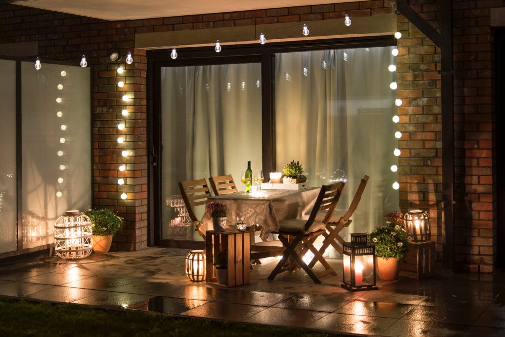 Summer evening terrace with candles, wine and lights, wet pavements