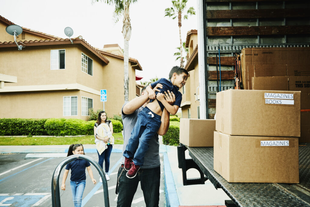 Father lifting smiling son into back of moving truck