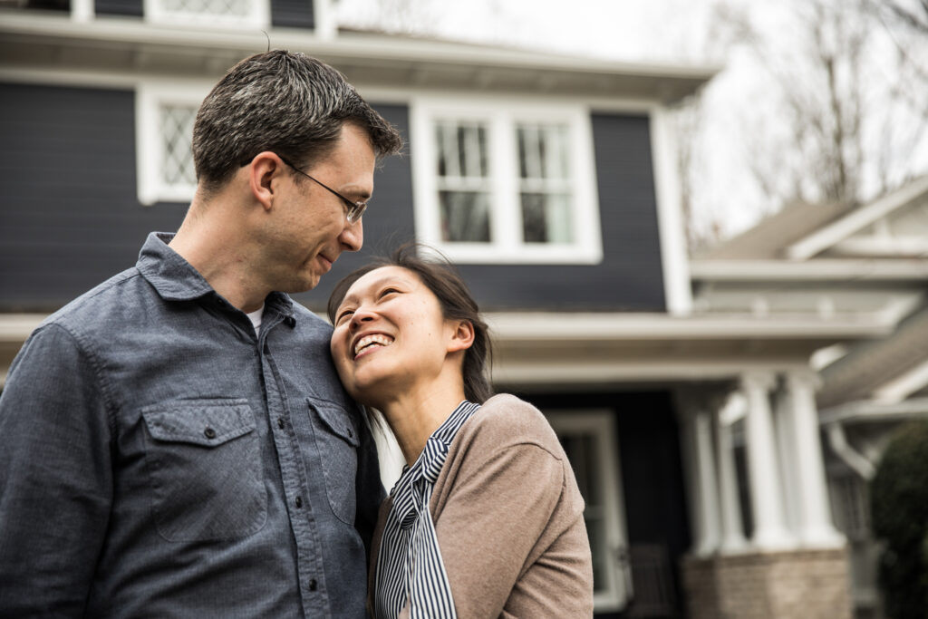 Couple standing in front of their new home