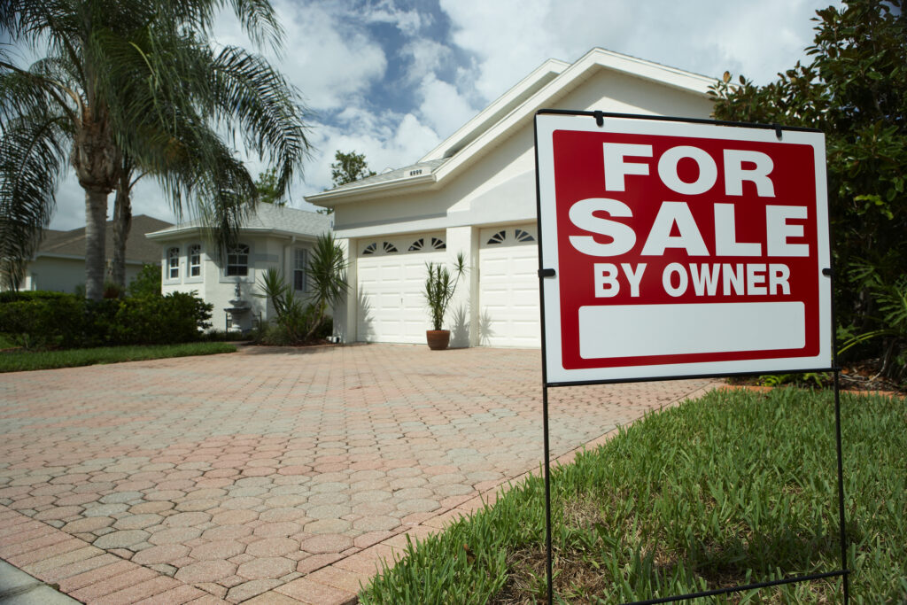 Home with a "for sale by owner" sign in the front