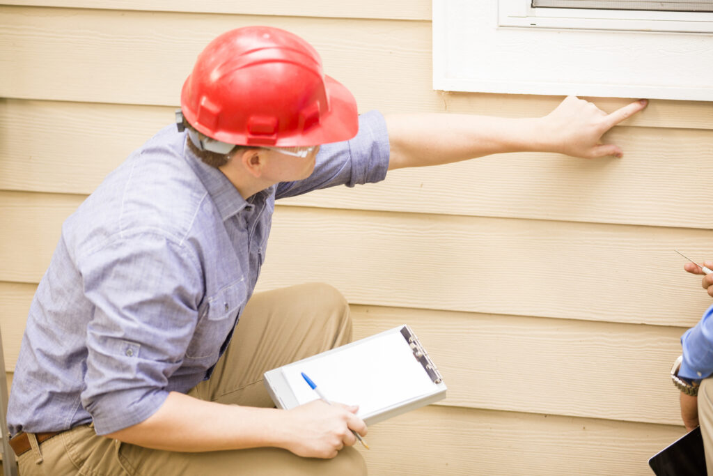 Home inspector checks the siding on a yellow house