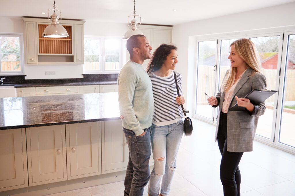 Realtor showing a house for sale to a couple, standing in kitchen