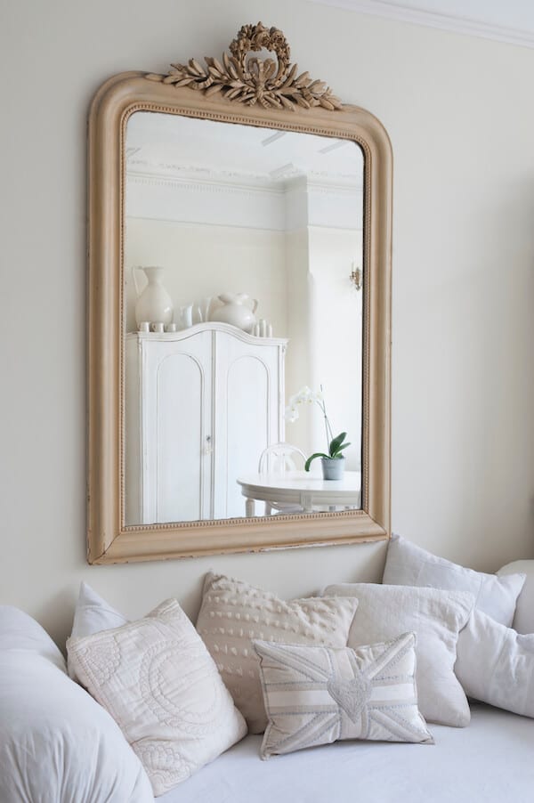 Room with white decor and gold mirror that makes the room look bigger