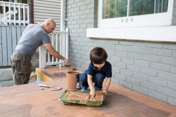 Father and son working together to paint the front porch