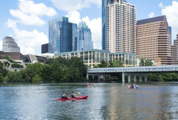 People canoeing on Lady Bird Lake in Austin with the Austin Skyline in the background.