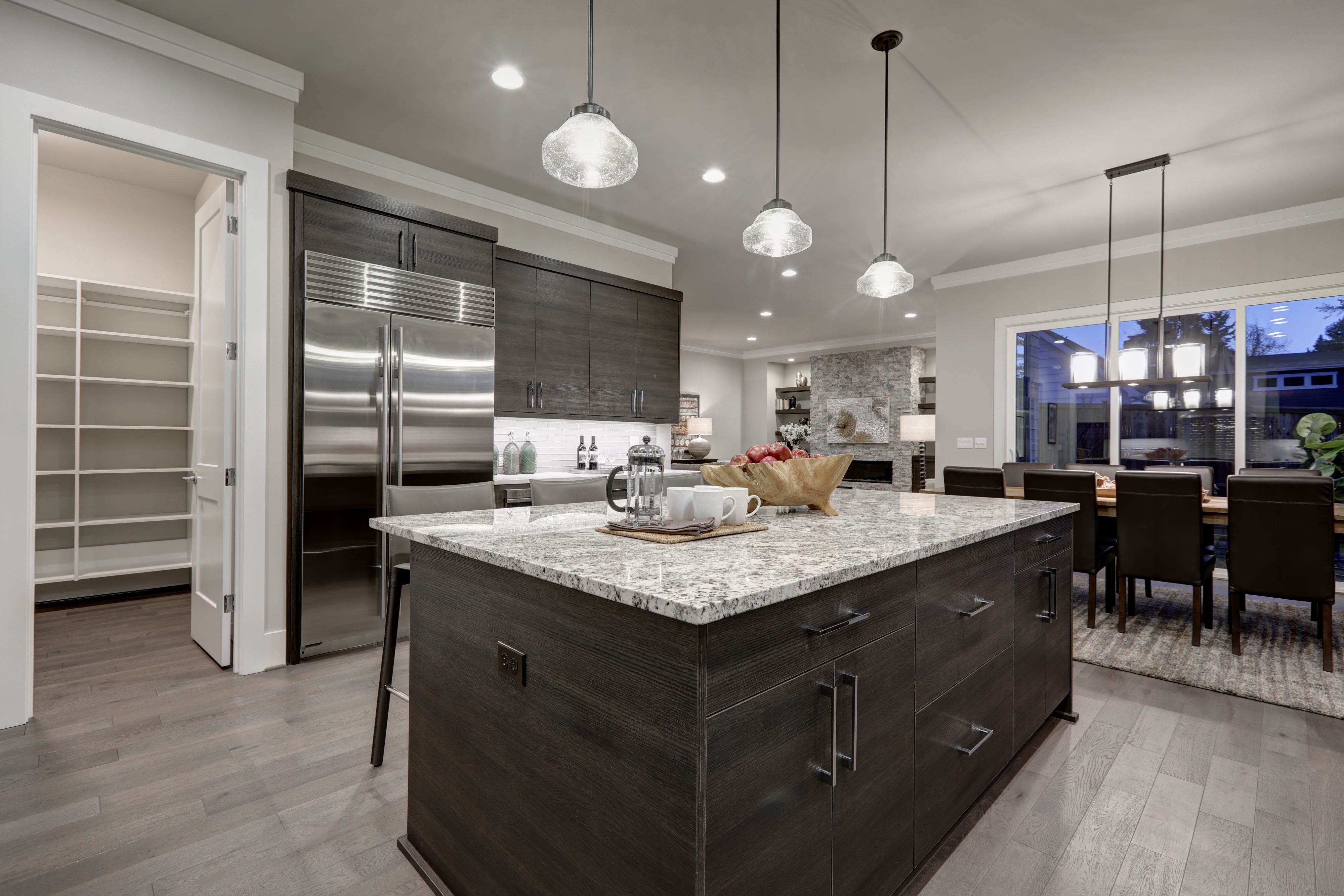 Luxury kitchen with dark gray cabinets on island, and modern light fixtures