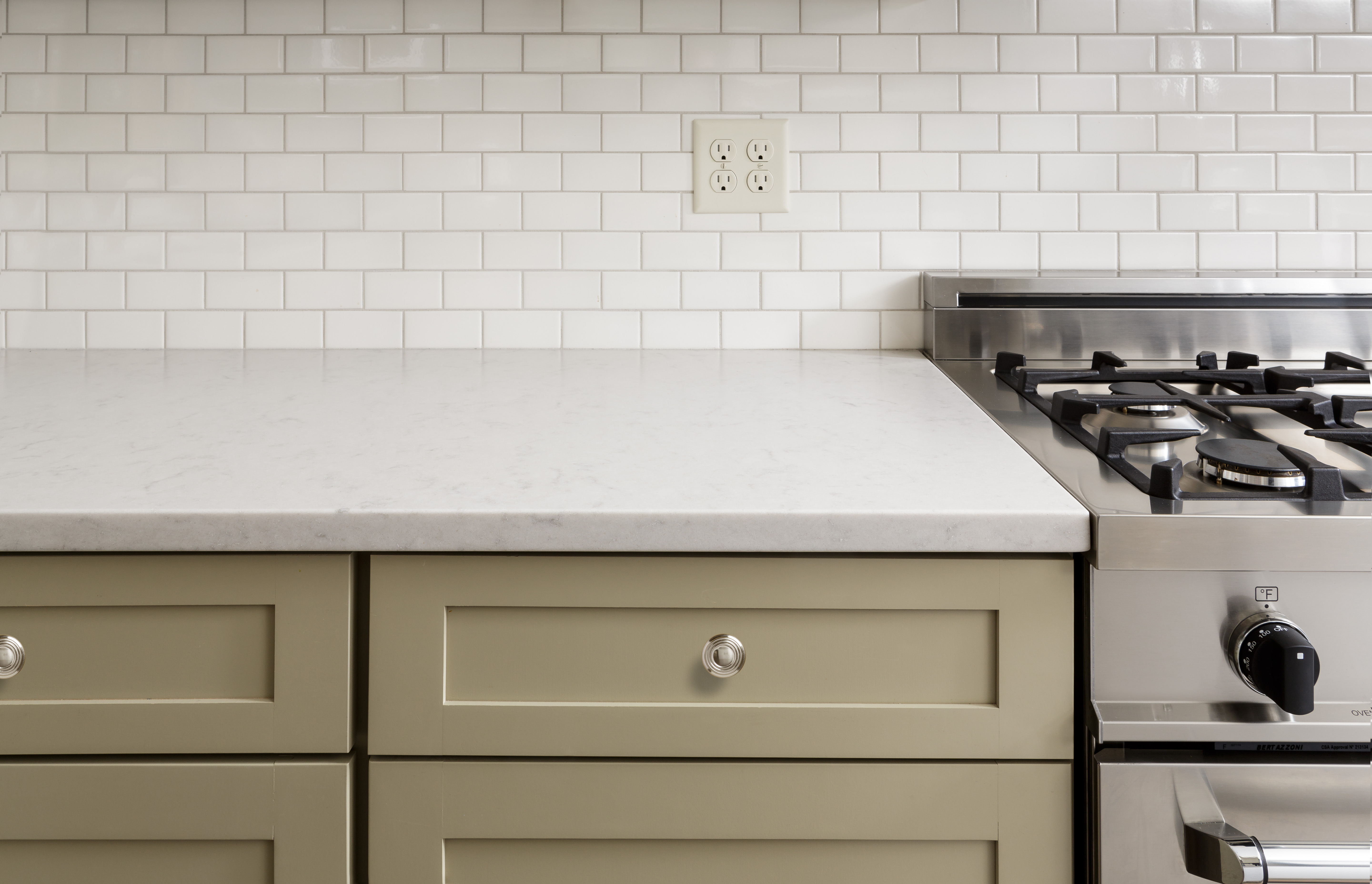 Khaki green kitchen cabinets with white subway tile backsplash