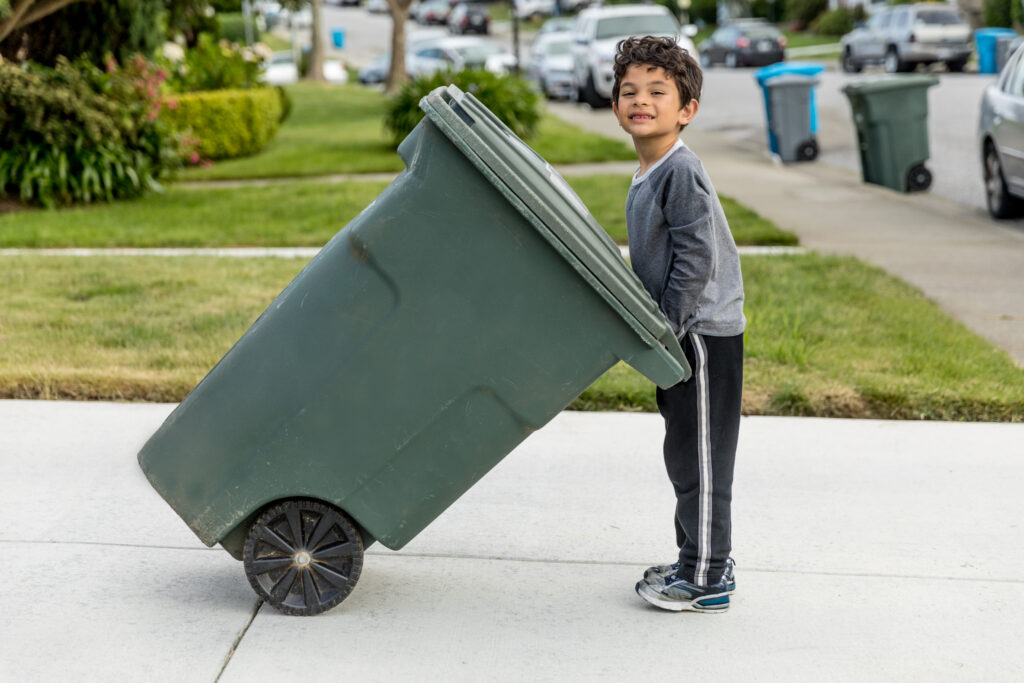 High quality stock photo of a young boy taking out the trash in an urban neighborhood.