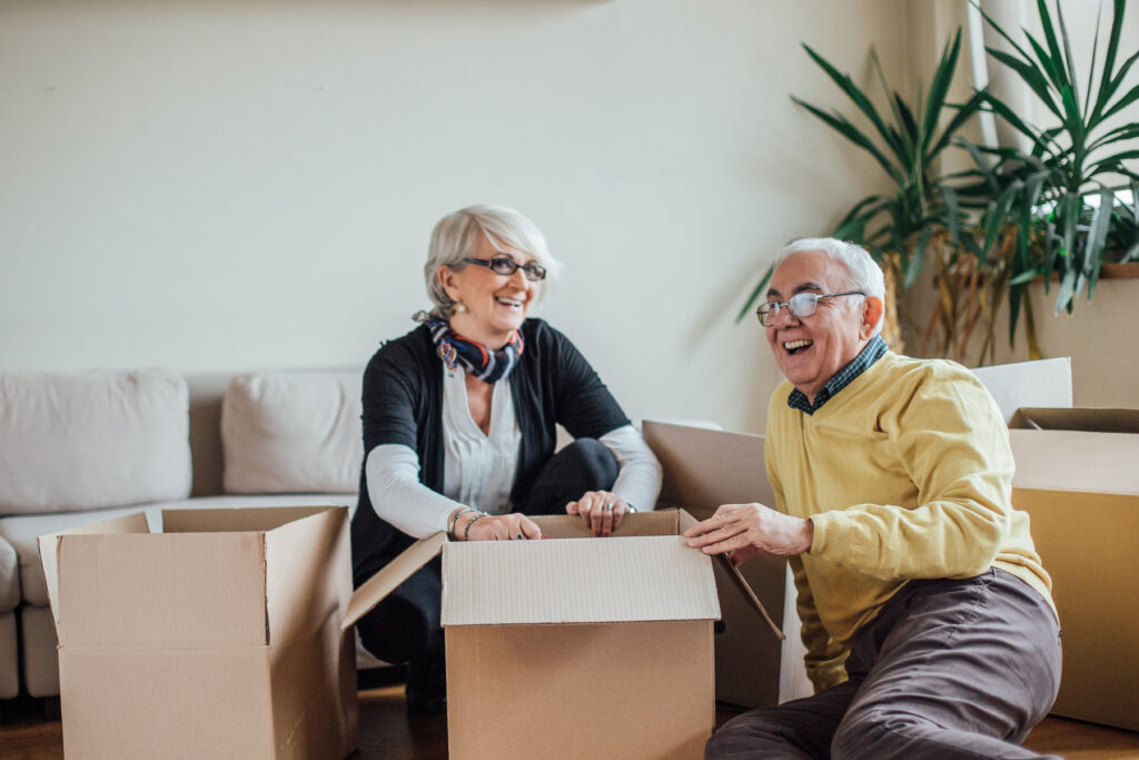 Mature couple smiling and unpacking paper containers at new apartment