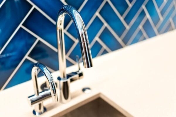 Modern blue tile backsplash behind sink in kitchen
