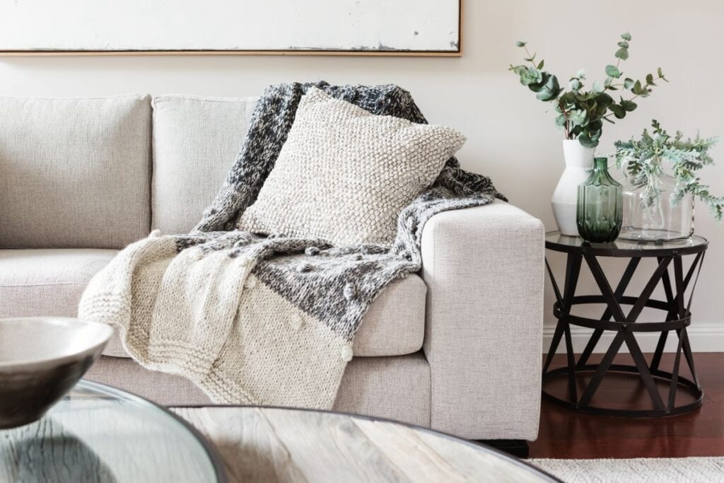 Comfortable white couch with throw pillow and blanket