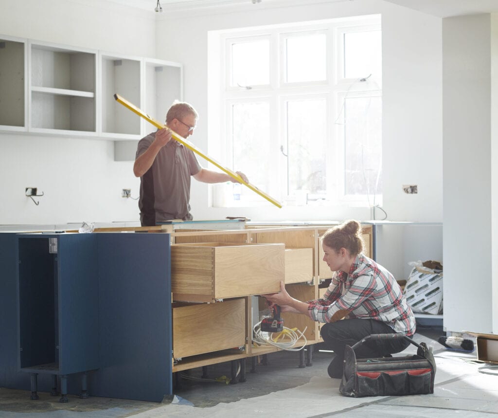 a female kitchen fitter prepping cupboards for worktop