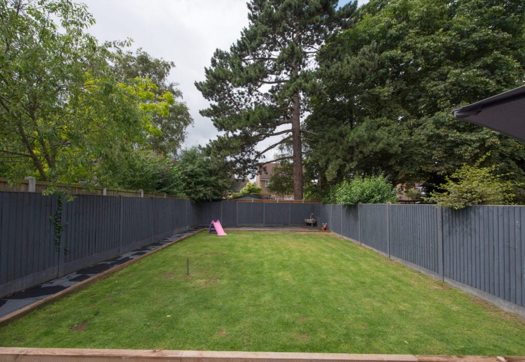 Una vista general de un jardín trasero con cercas de madera gris de una casa