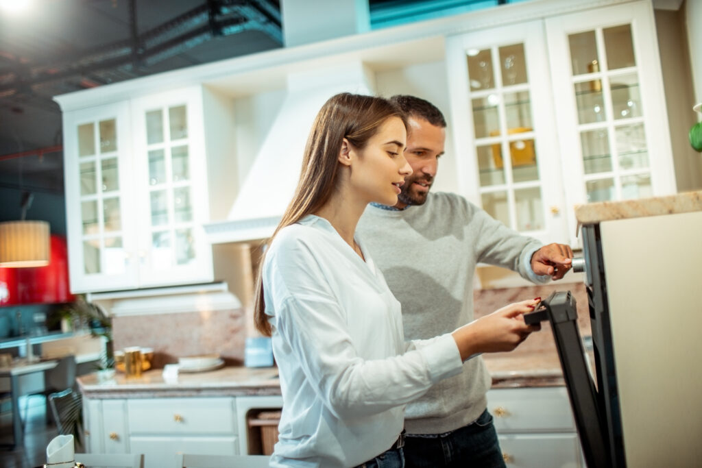 Husband and wife looking into buying a new modular electric stove in a kitchen accessories store.