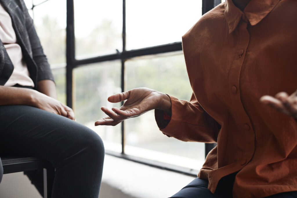 Midsection of businesswoman gesturing while sitting by window at workplace