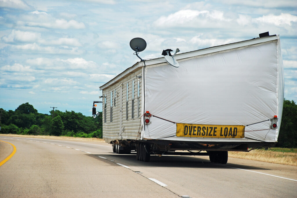 Half of double-wide house trailer being transported along interstate highway