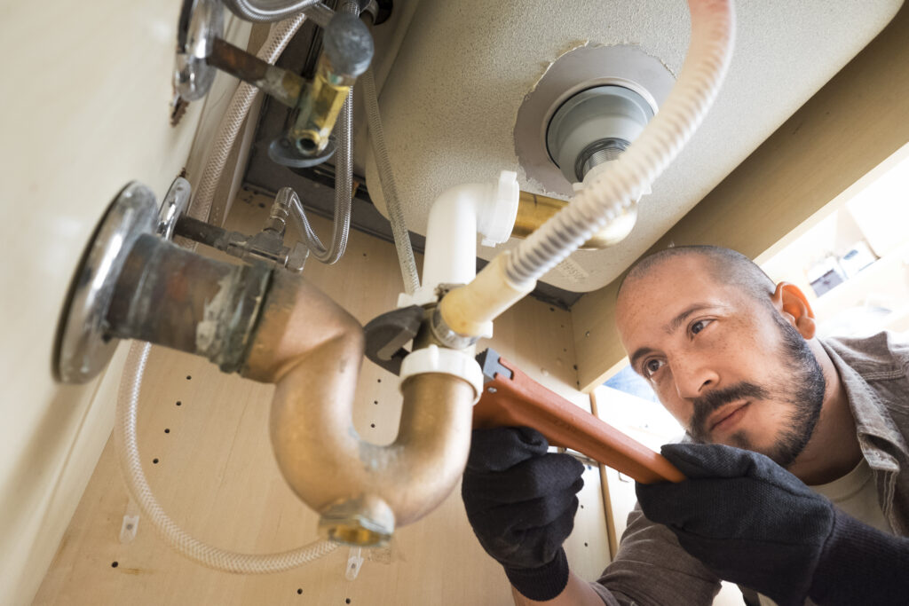 Hispanic plumber working under sink